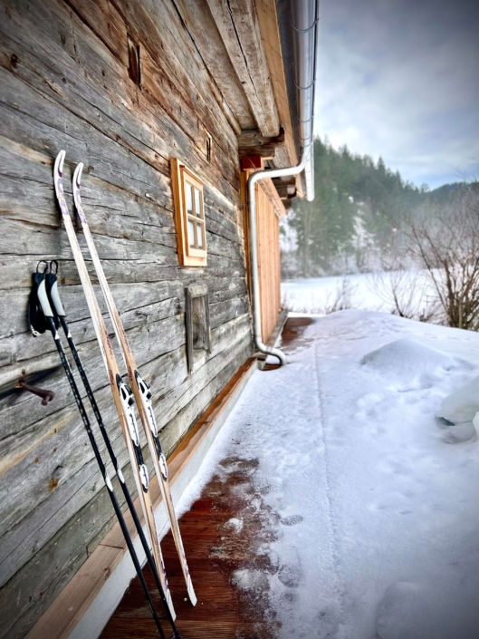 Das Chalet als perfekte Ausgangsbasis für Wintersport, Langlaufski lehnen exemparisch an der Hauswand